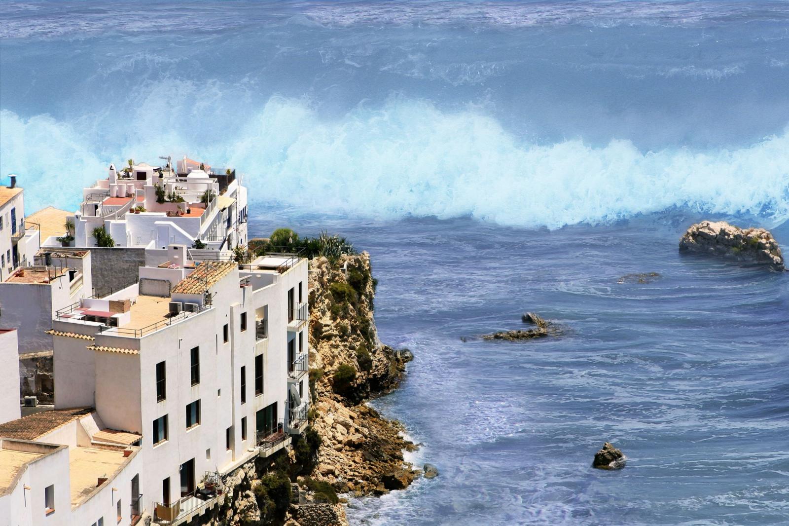 Une grosse vague s'approche d'une côte remplie d'habitations