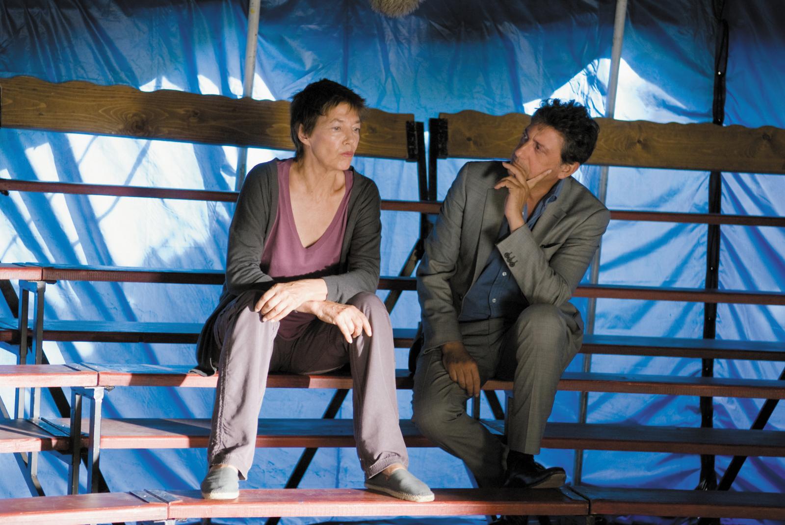 Couple assis sur les gradins d'un cirque au chapiteau bleu ciel