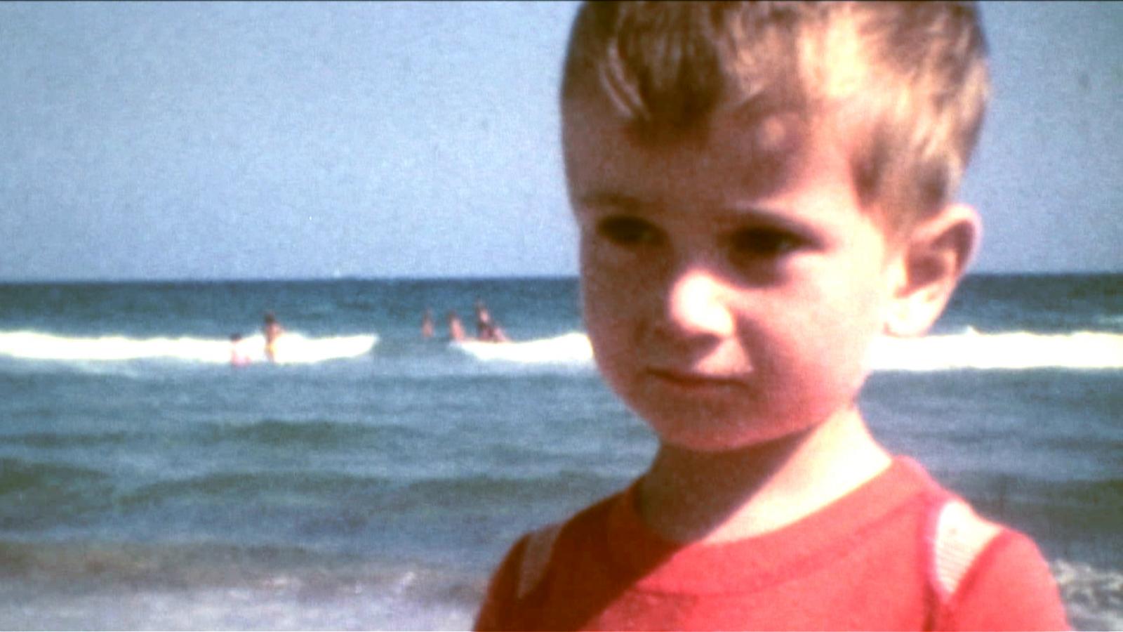 Petit garçon portant un t-shirt rouge, devant la mer