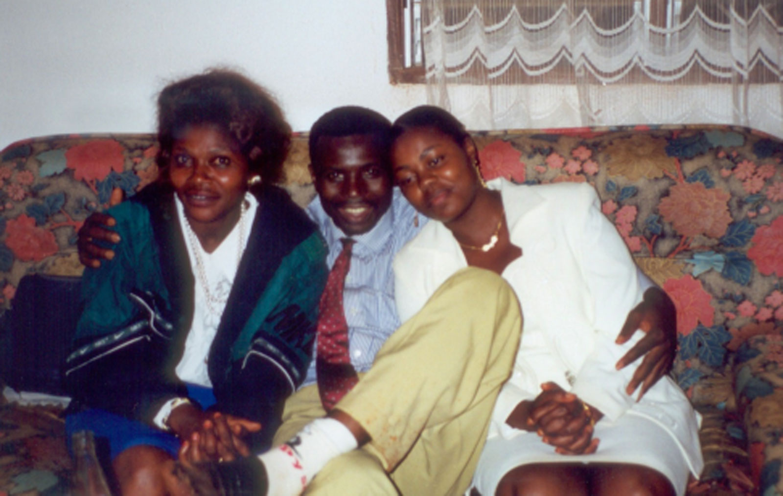 Photo de famille d'un homme et de ses deux femmes, assis sur un canapé