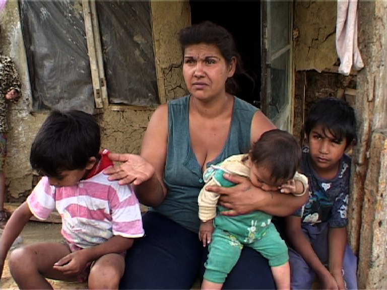 Une mère rom, entourée de ses trois enfants, fait la manche