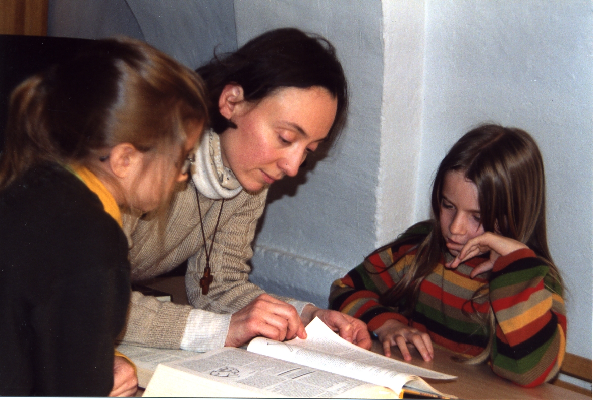 Nathalie, aidant deux petites filles à faire leurs devoirs